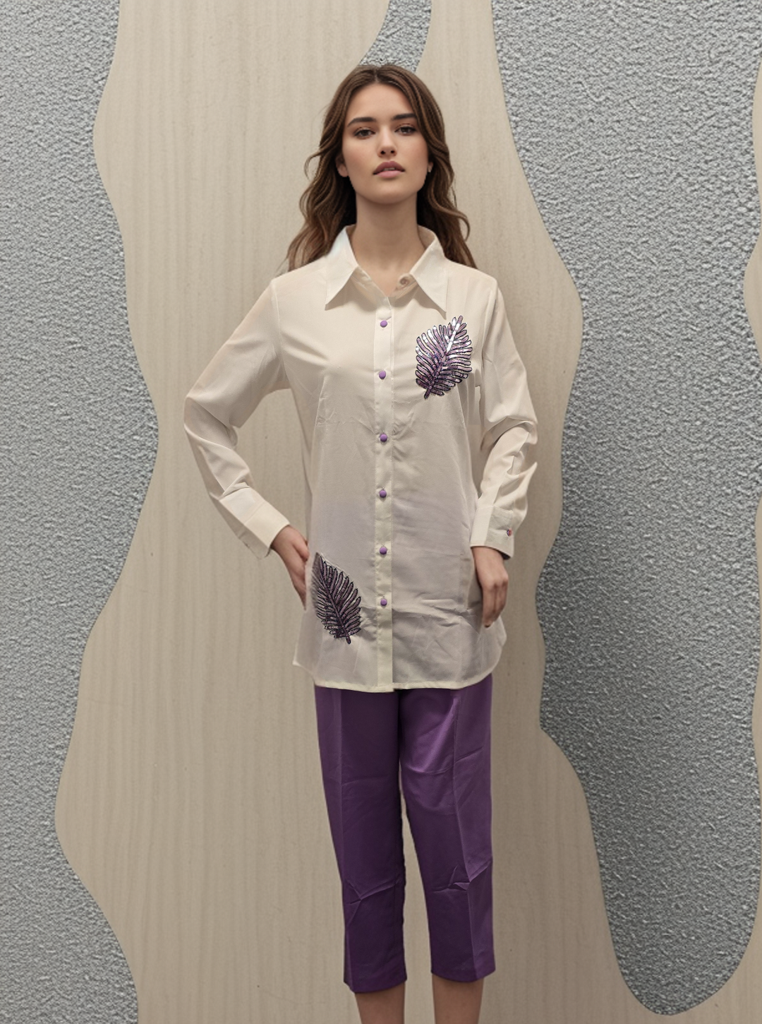 a woman standing in front of a wall wearing purple pants